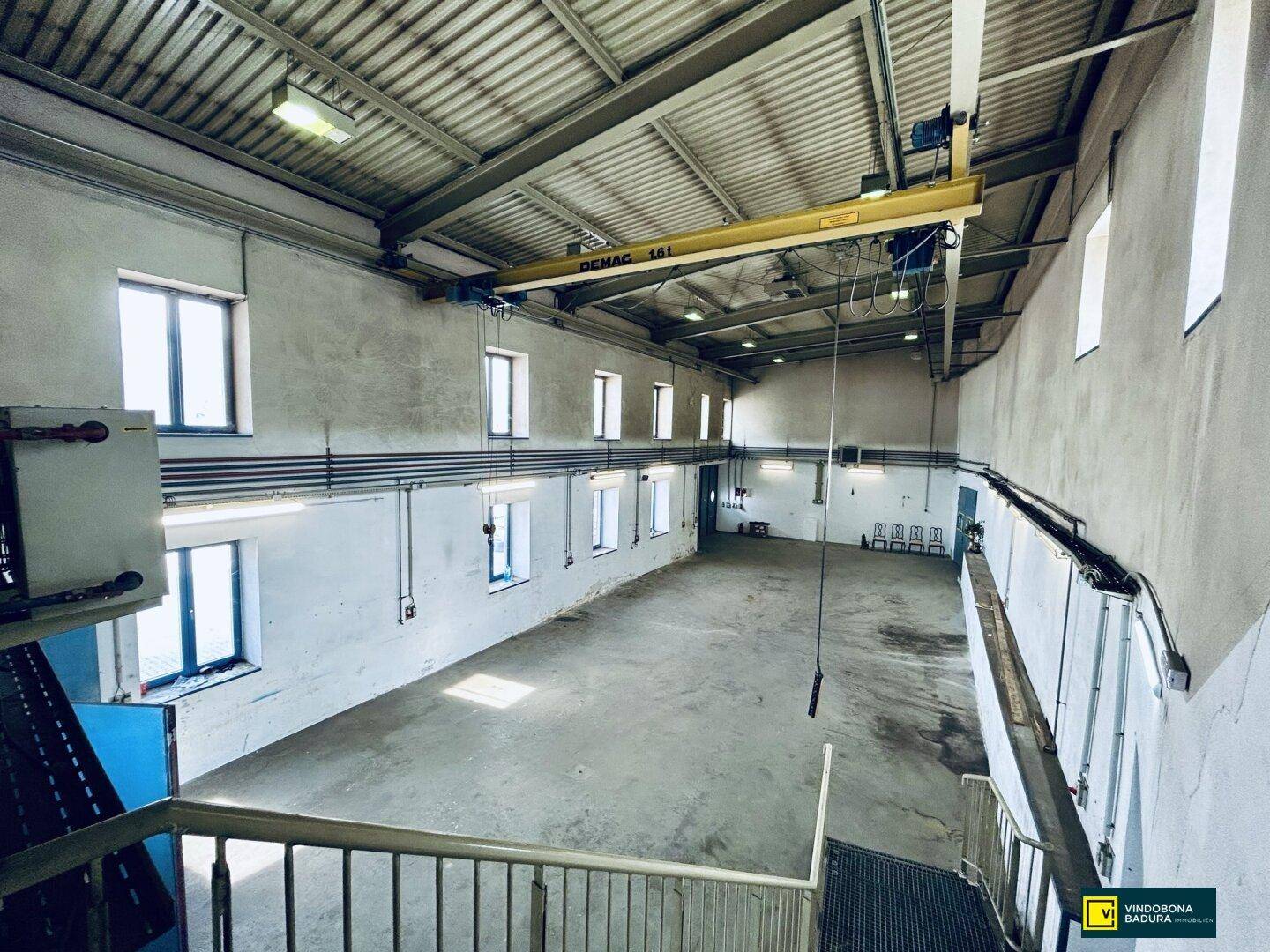 Weitläufiger Industrie- oder Lagerraum mit Krananlage, hohen Decken und natürlichem Lichteinfall.