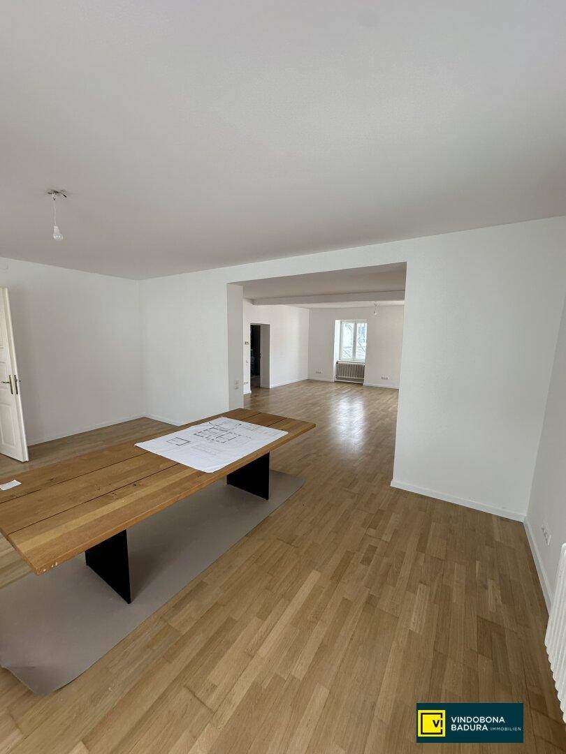 Heller Wohnbereich mit Holzparkettboden und einem großen Holztisch, bereit zur Gestaltung.