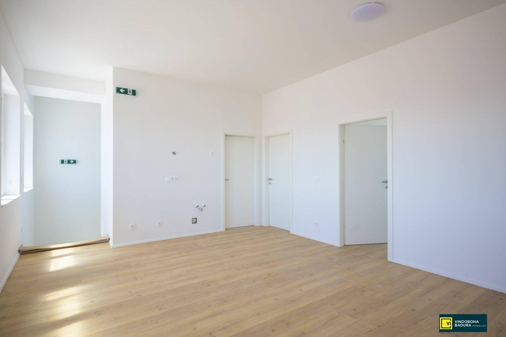 Heller Büroraum mit hellem Laminatboden und weißen Wänden, bereit für die Einrichtung.