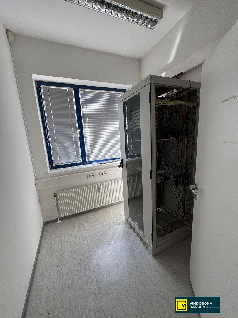 Kleiner Raum mit Serverschrank, Fenster und Heizkörper, ideal für technische Infrastruktur.