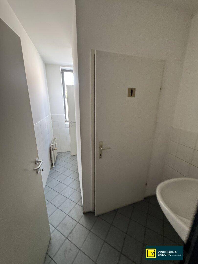Einfacher Toilettenbereich mit Waschbecken und gefliestem Boden, funktional und sauber.