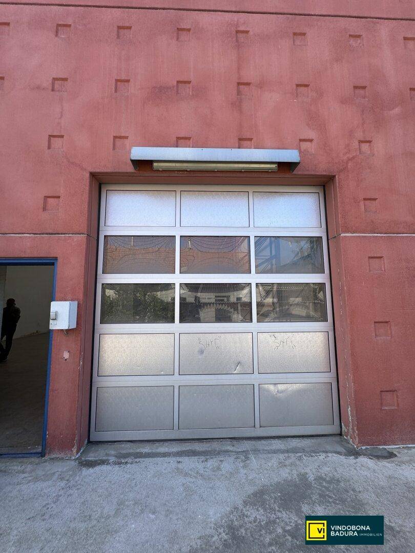 Großes Garagentor an der roten Fassade des Industriegebäudes, funktional und robust.