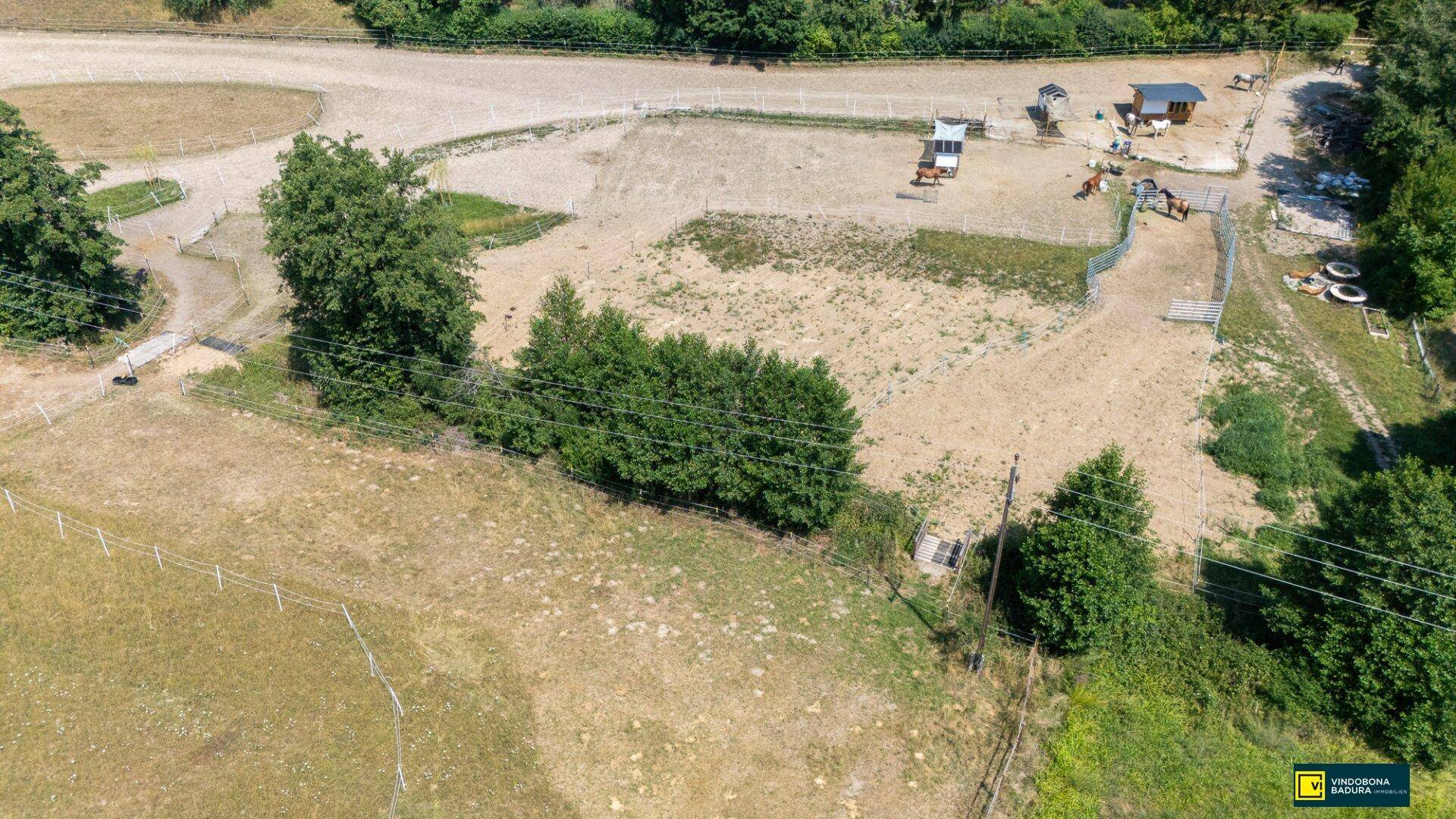 Luftaufnahme des Anwesens mit Stallungen, Reitplatz und weitläufigen Koppeln in ländlicher Umgebung.