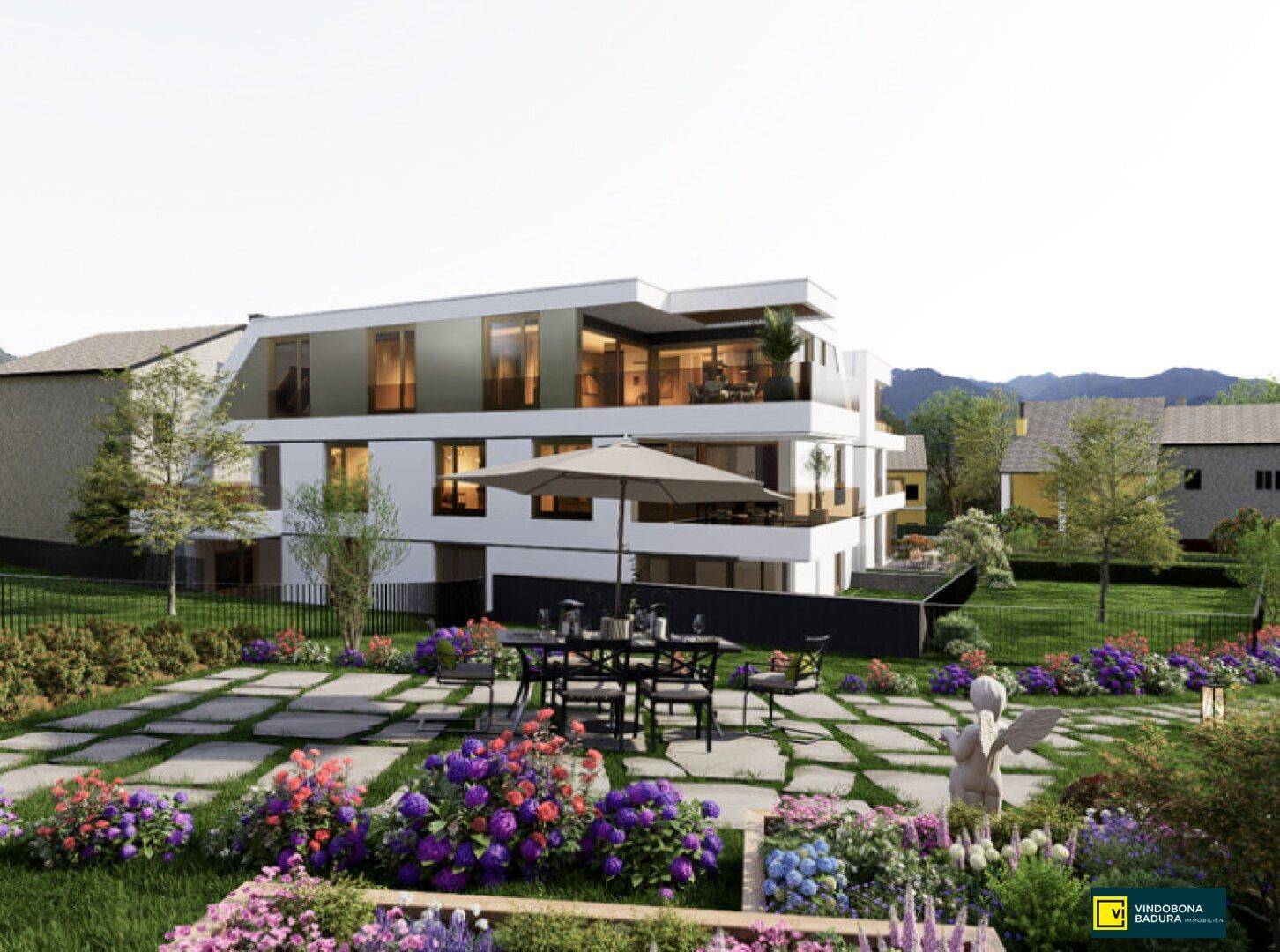 Großzügiger Gartenbereich mit gepflasterter Terrasse, Esstisch und bunter Blumenbepflanzung.