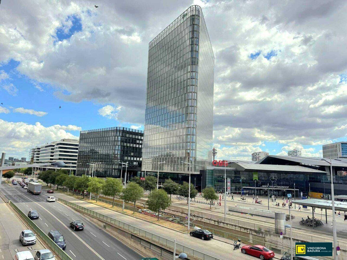 Beeindruckender Blick auf ein modernes Hochhaus mit Glasfassade und den Wiener Hauptbahnhof.