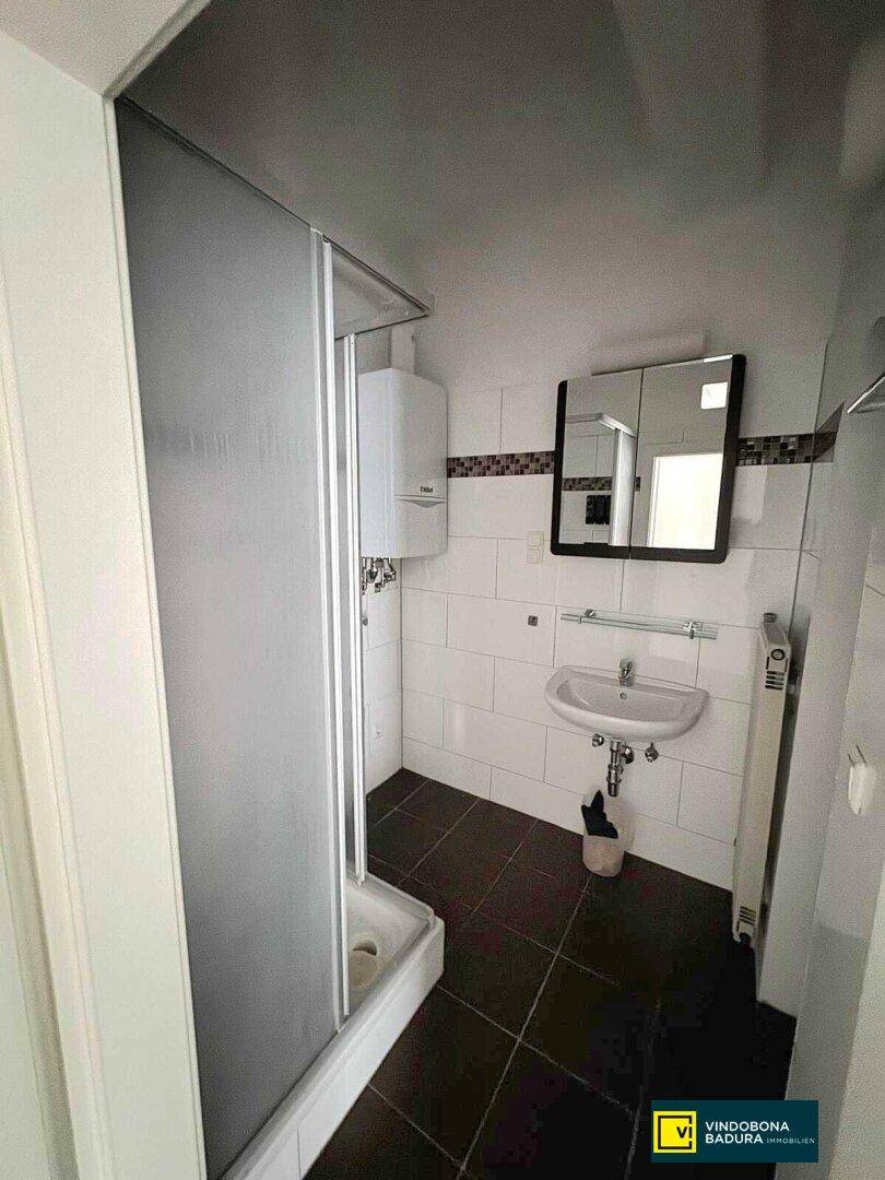 Badezimmer mit Duschkabine, Waschbecken und einem Spiegelschrank über dem Waschtisch.