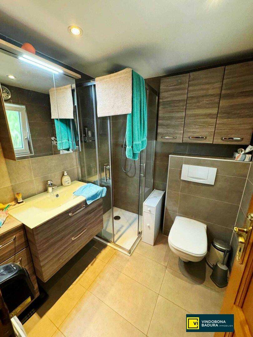 Modernes Badezimmer mit Duschkabine, wandhängendem WC und einem einzelnen Waschbecken.
