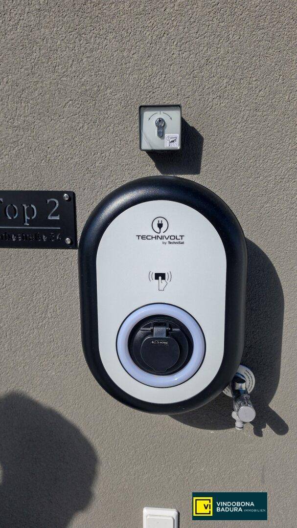 Ladestation für Elektrofahrzeuge an der Außenwand, mit 'Technivolt' Beschriftung.