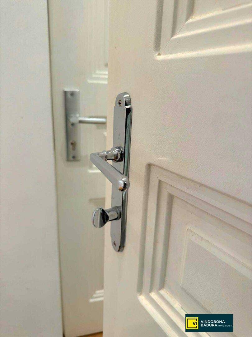 Nahaufnahme einer weißen Innentür mit modernem, glänzendem Türgriff.