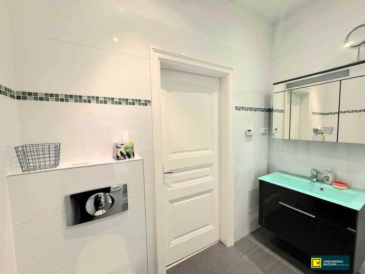 Modernes Badezimmer mit Wand-WC, Waschbecken und Spiegelschrank.