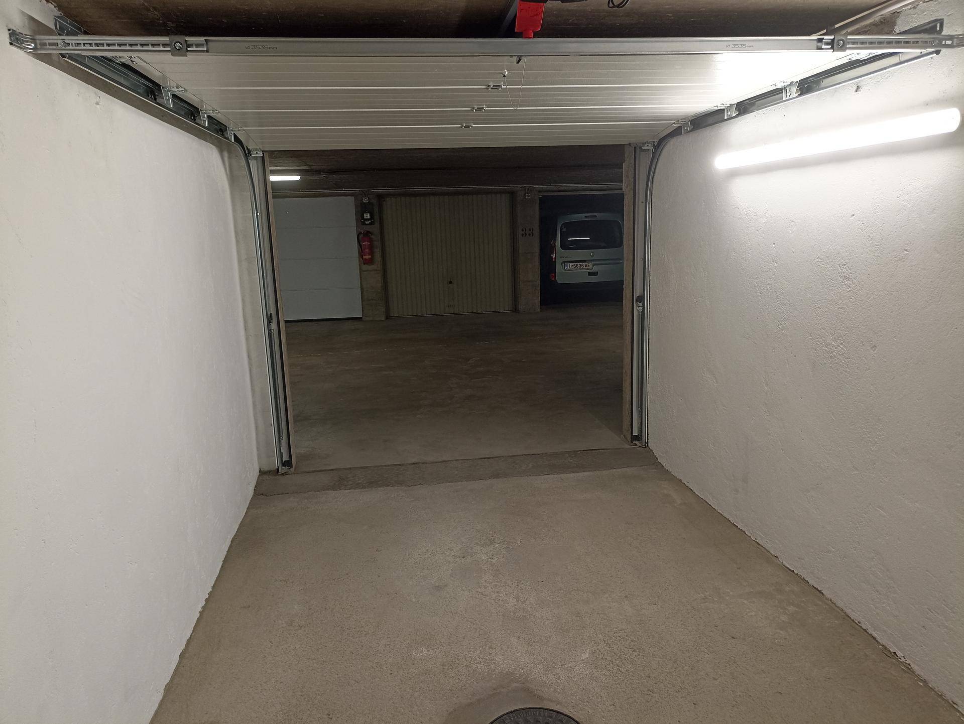 Blick aus der Garagenbox in die Tiefgarage mit weiteren Stellplätzen und Fahrzeugen.