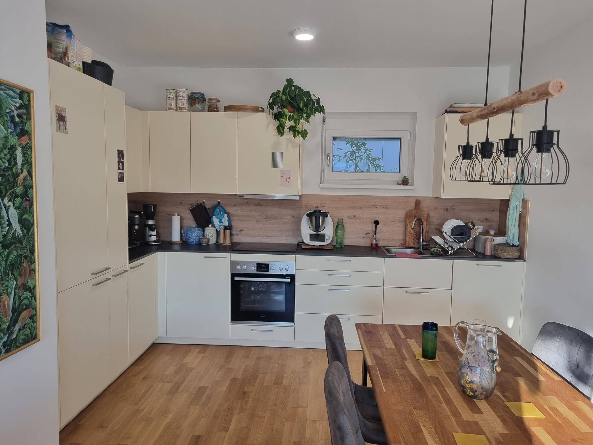 Helle, moderne Küche mit beigen Schränken, Holzarbeitsplatte und Essbereich für gemeinsame Mahlzeiten.