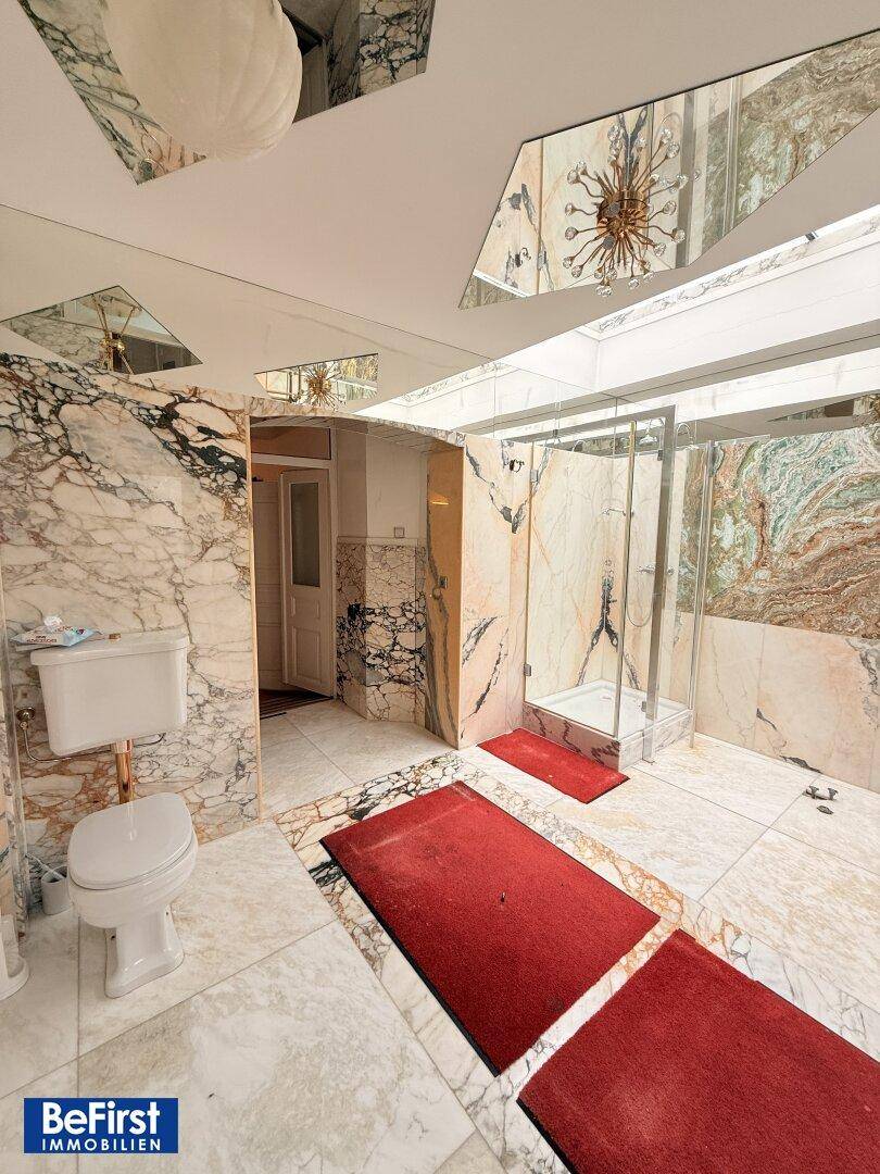 Luxuriöses Badezimmer mit Marmorwänden, Fliesenboden und einer modernen Duschkabine.