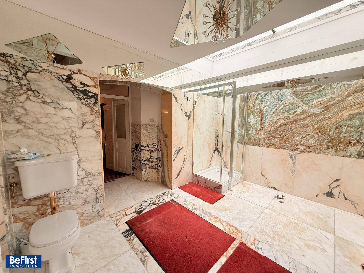 Luxuriöses Badezimmer mit Marmorwänden, Fliesenboden und einer modernen Duschkabine.