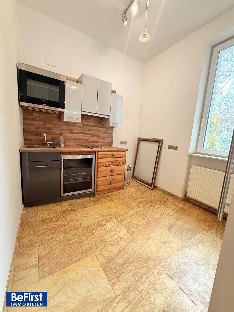 Kleine Küchenzeile mit Holztheke, Einbaugeräten und Fenster für natürliches Licht.