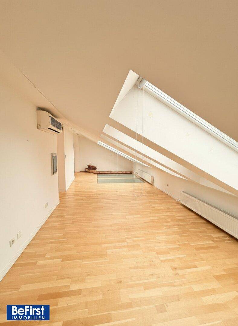 Heller Dachgeschossraum mit schrägen Decken, Parkettboden und mehreren Dachfenstern.