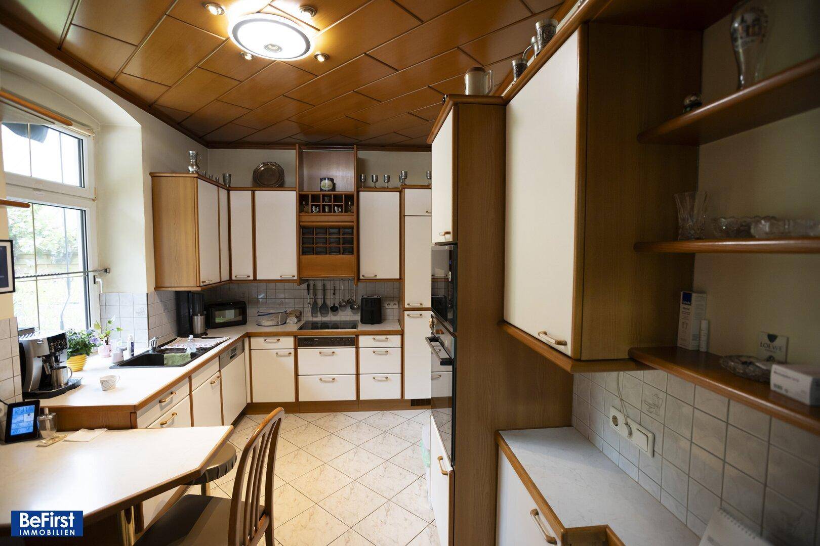 Funktionale Küche mit Einbauschränken, Holzdecke und einem Essbereich am Fenster.