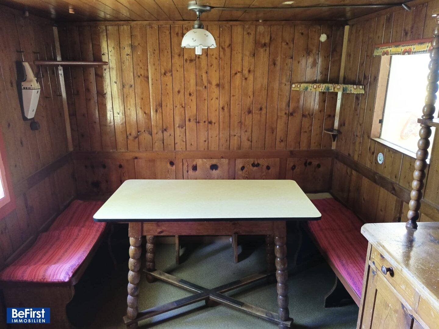 Gemütlicher Wohnraum mit Holztäfelung, Esstisch und eingebauten Sitzbänken.