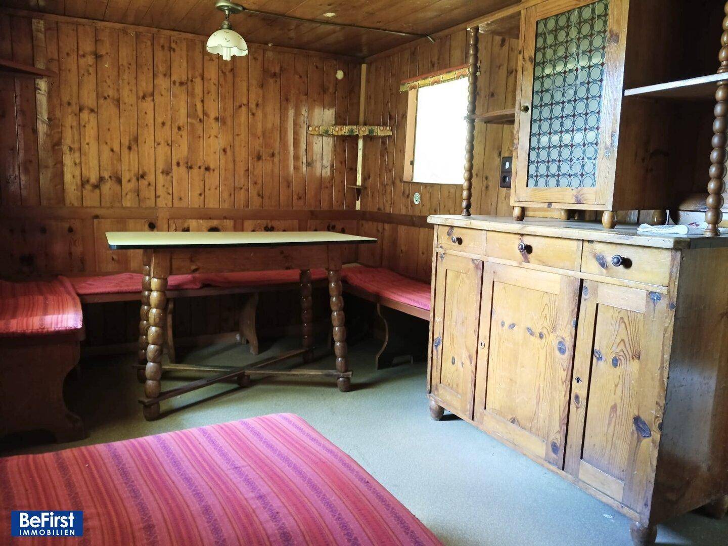 Rustikaler Wohnraum mit Holztäfelung, Holztisch und eingebauten Sitzbänken in traditionellem Stil.
