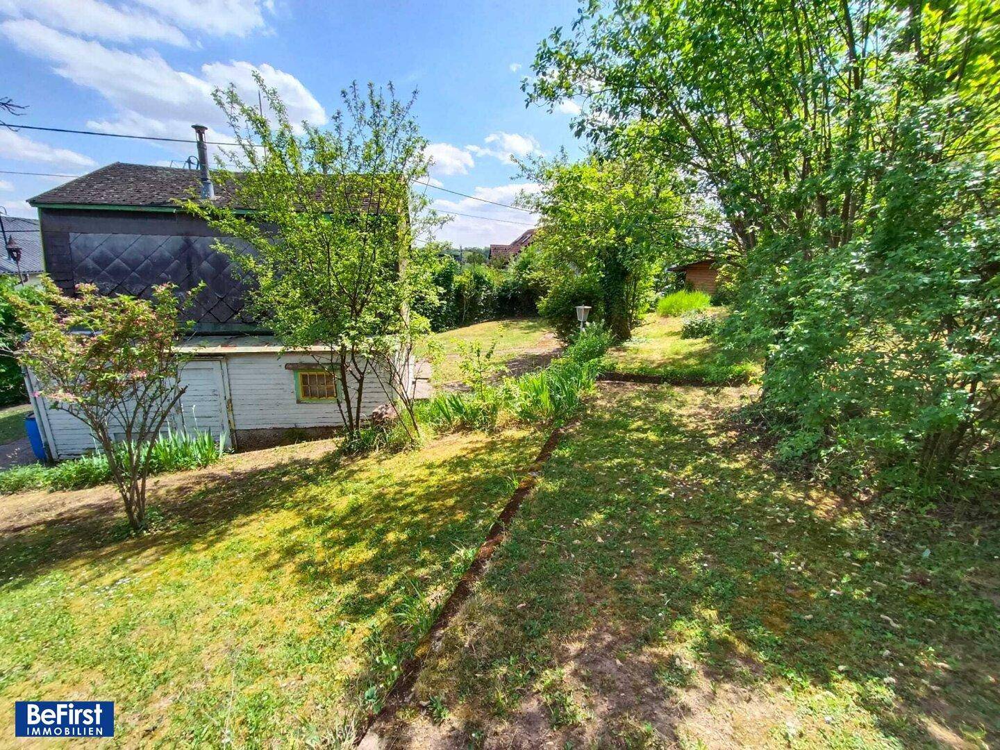 Weitläufiger Gartenbereich mit Bäumen und Sträuchern hinter dem rustikalen Haus.