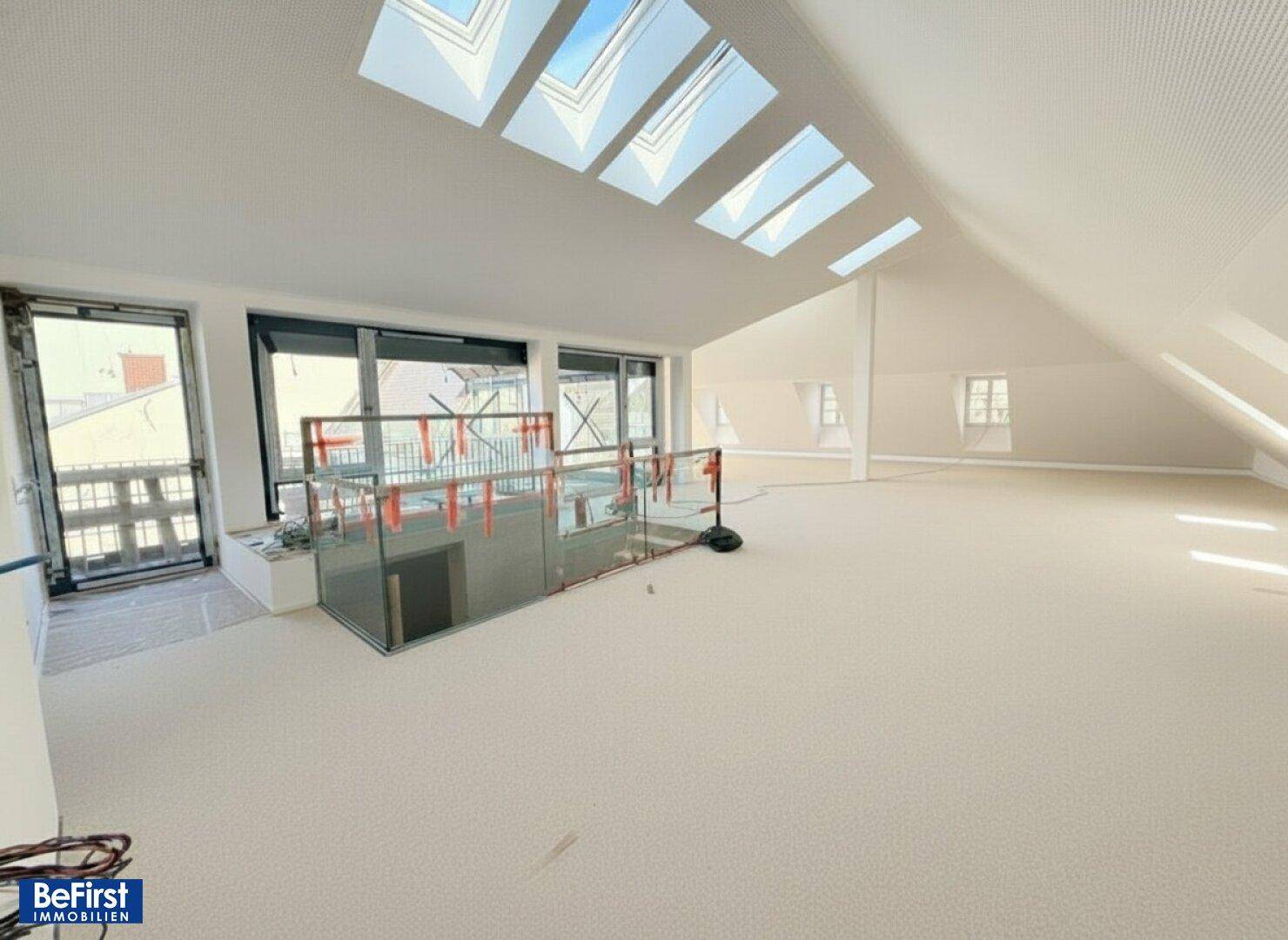 Geräumiger, heller Loftbereich im Dachgeschoss mit vielen Dachfenstern und Glasgeländer.