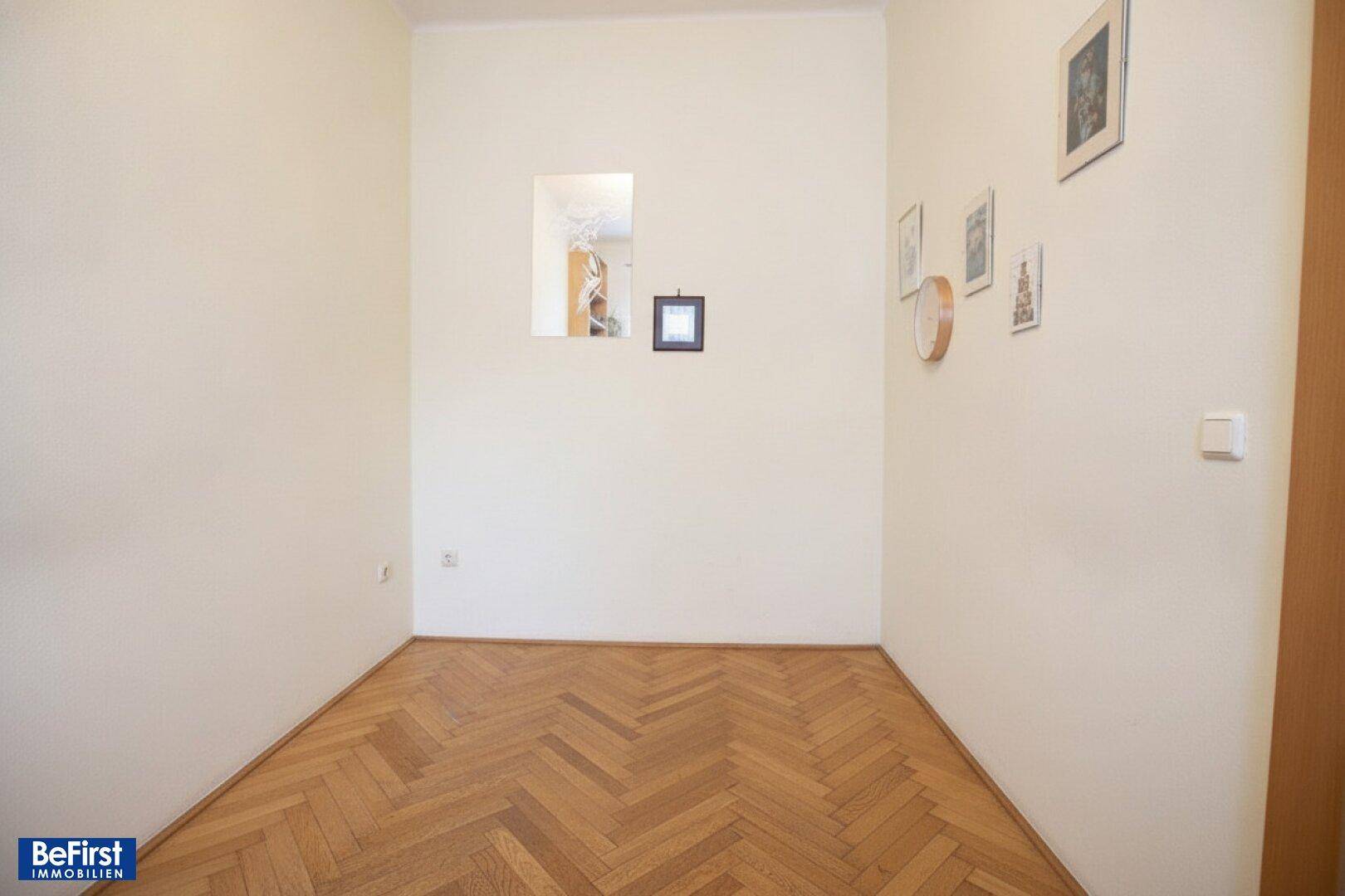 Heller, leerer Raum mit Fischgrätparkett und weißen Wänden, ideal als Schlafzimmer oder Büro.