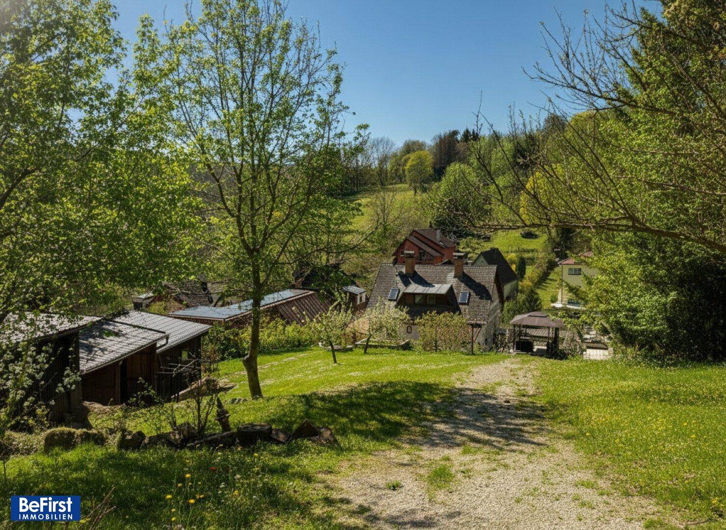 Weitläufiger grüner Gartenbereich mit Bäumen und Blick auf die umliegende ländliche Landschaft.