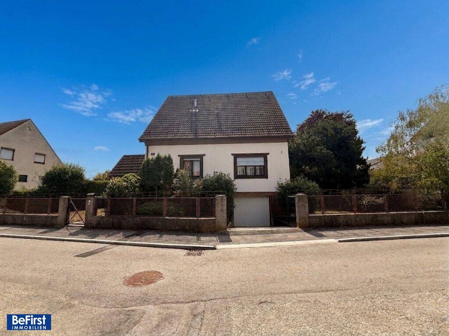 Vorderansicht eines Einfamilienhauses mit Satteldach und integrierter Garage von der Straße aus.