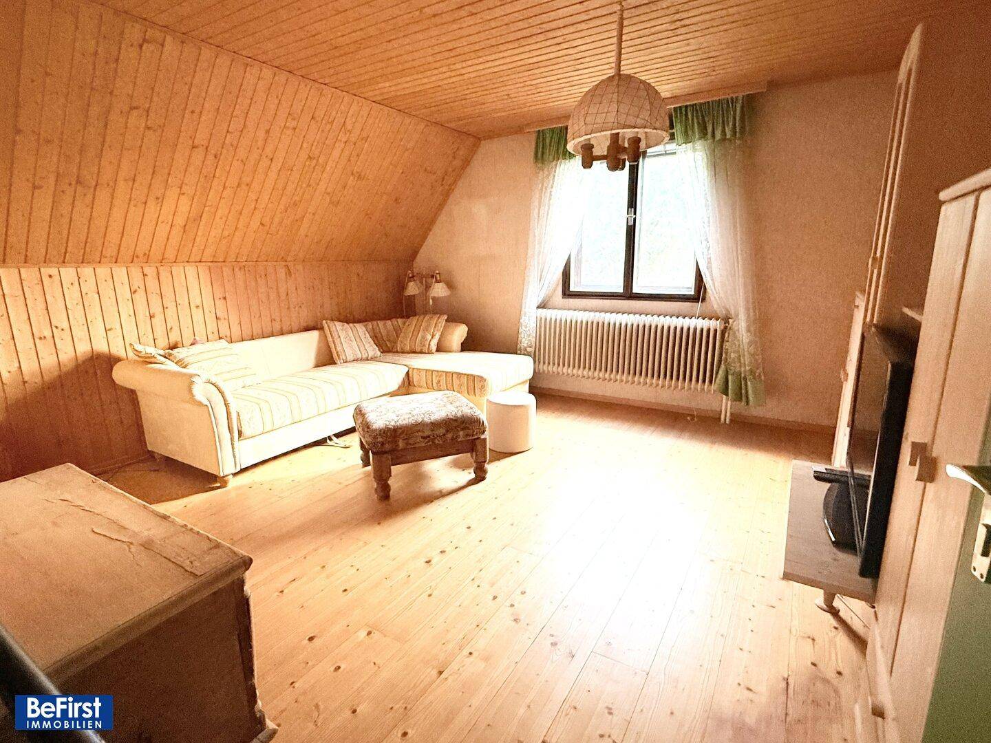Gemütliches Schlafzimmer im Dachgeschoss mit Holzverkleidung und schrägen Wänden.