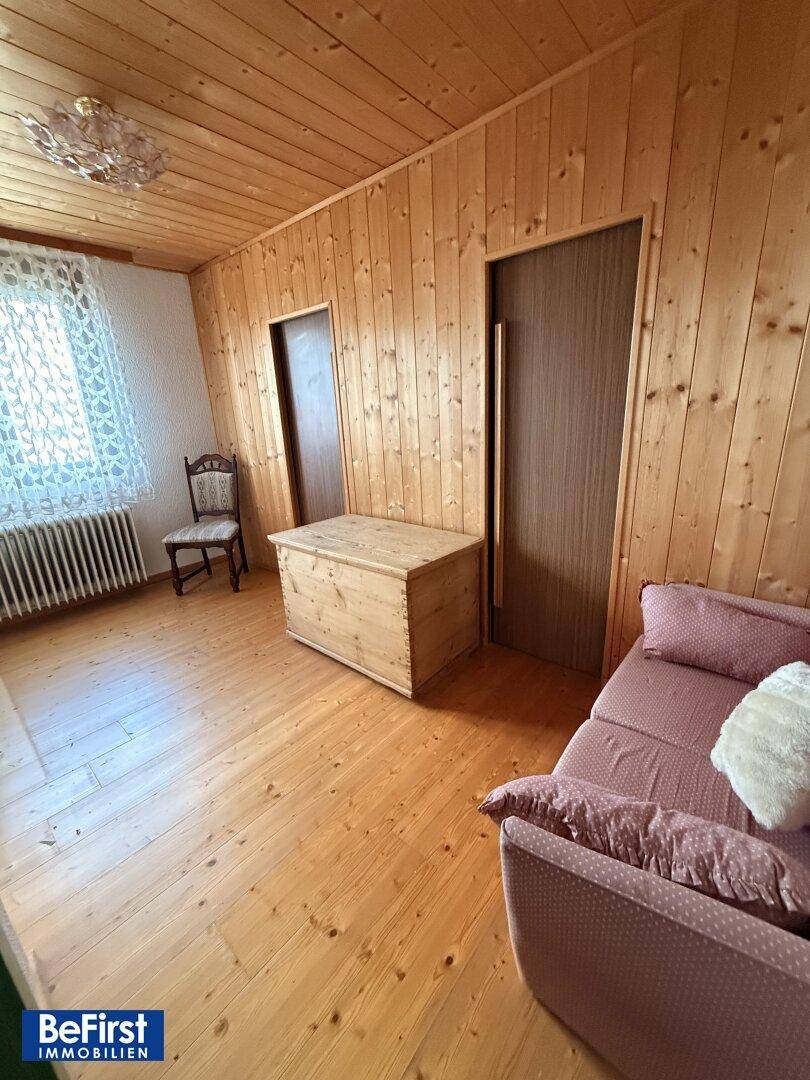 Schlafzimmer mit Holzvertäfelung, Holzboden und traditioneller Einrichtung.