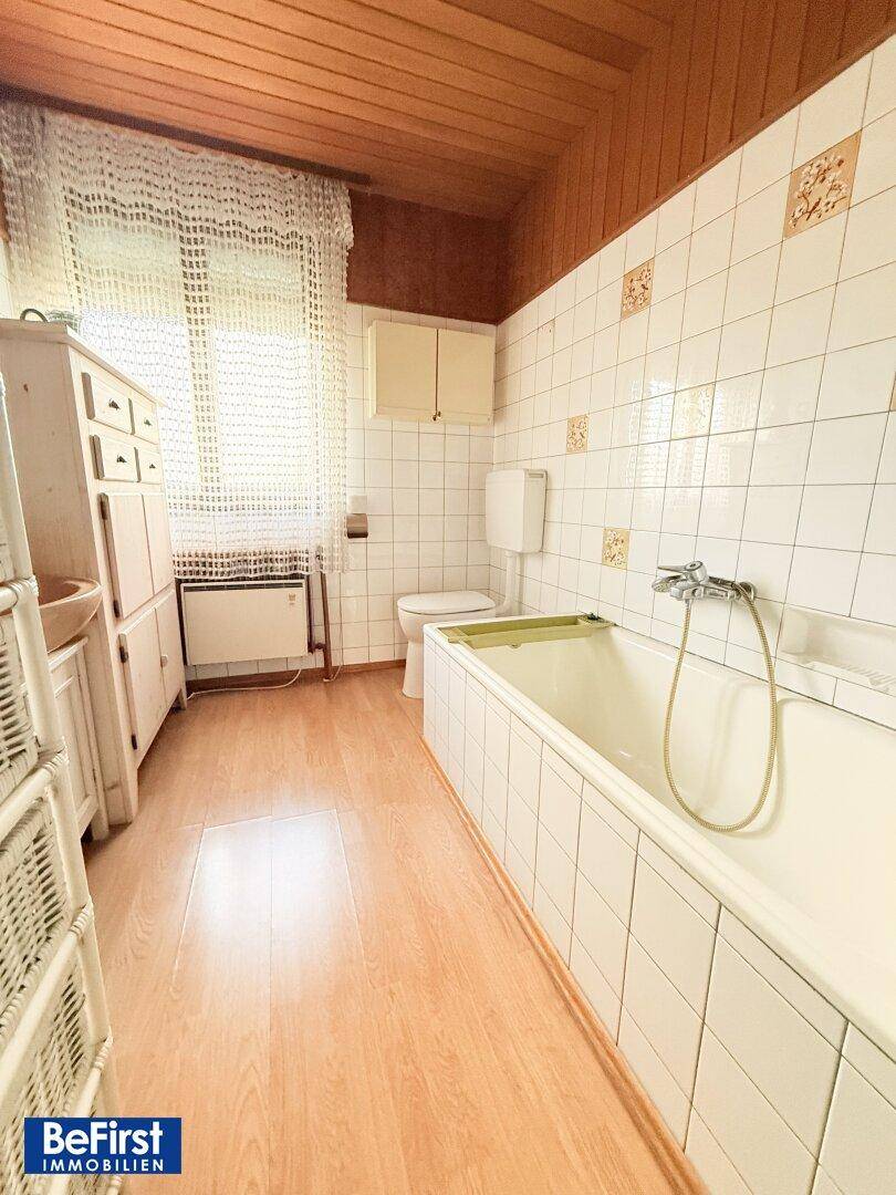 Badezimmer mit Badewanne, Fenster und weißen Fliesen im traditionellen Stil.