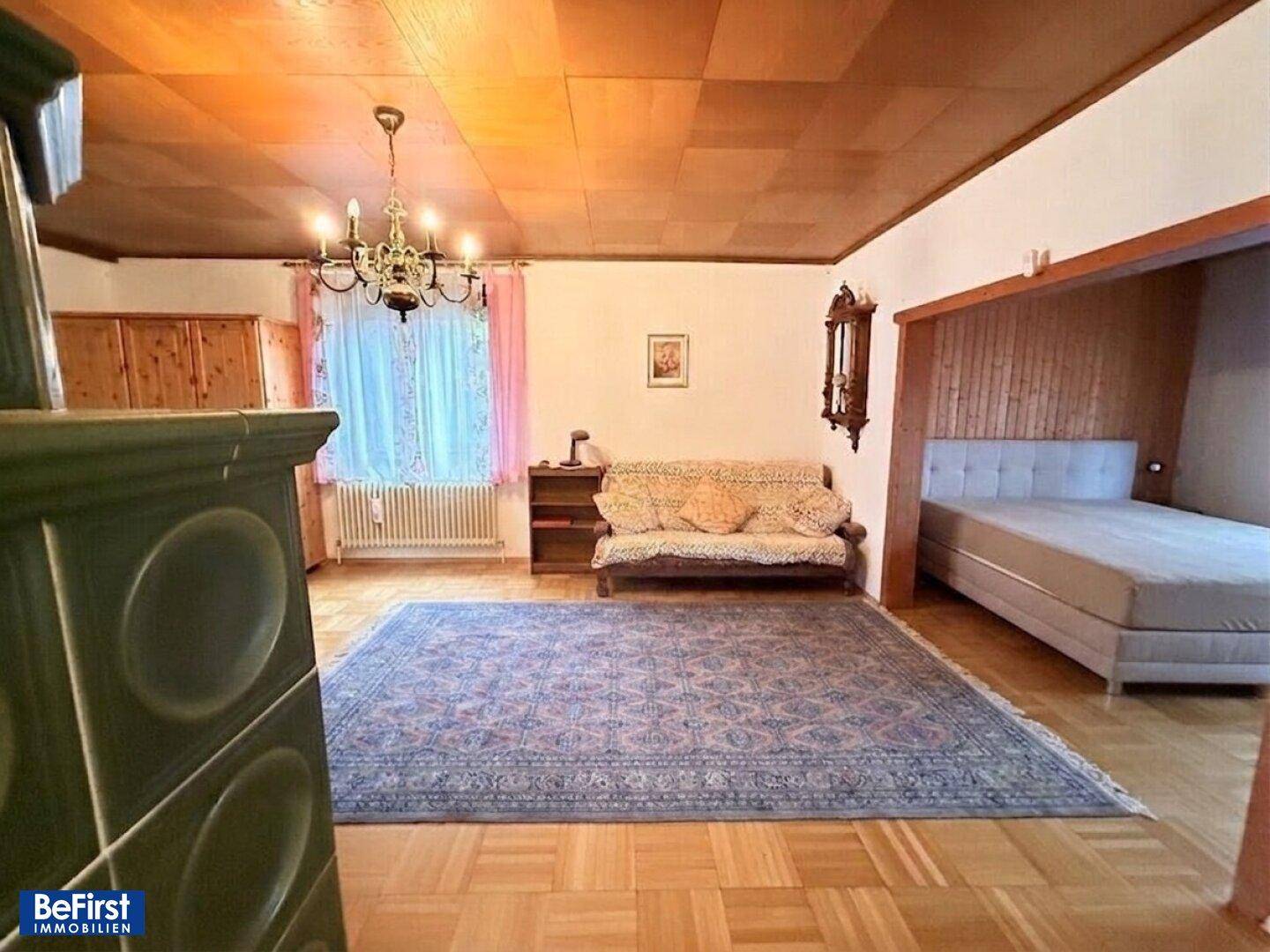 Geräumiges Wohnzimmer mit Parkettboden, Kachelofen und traditioneller Einrichtung.