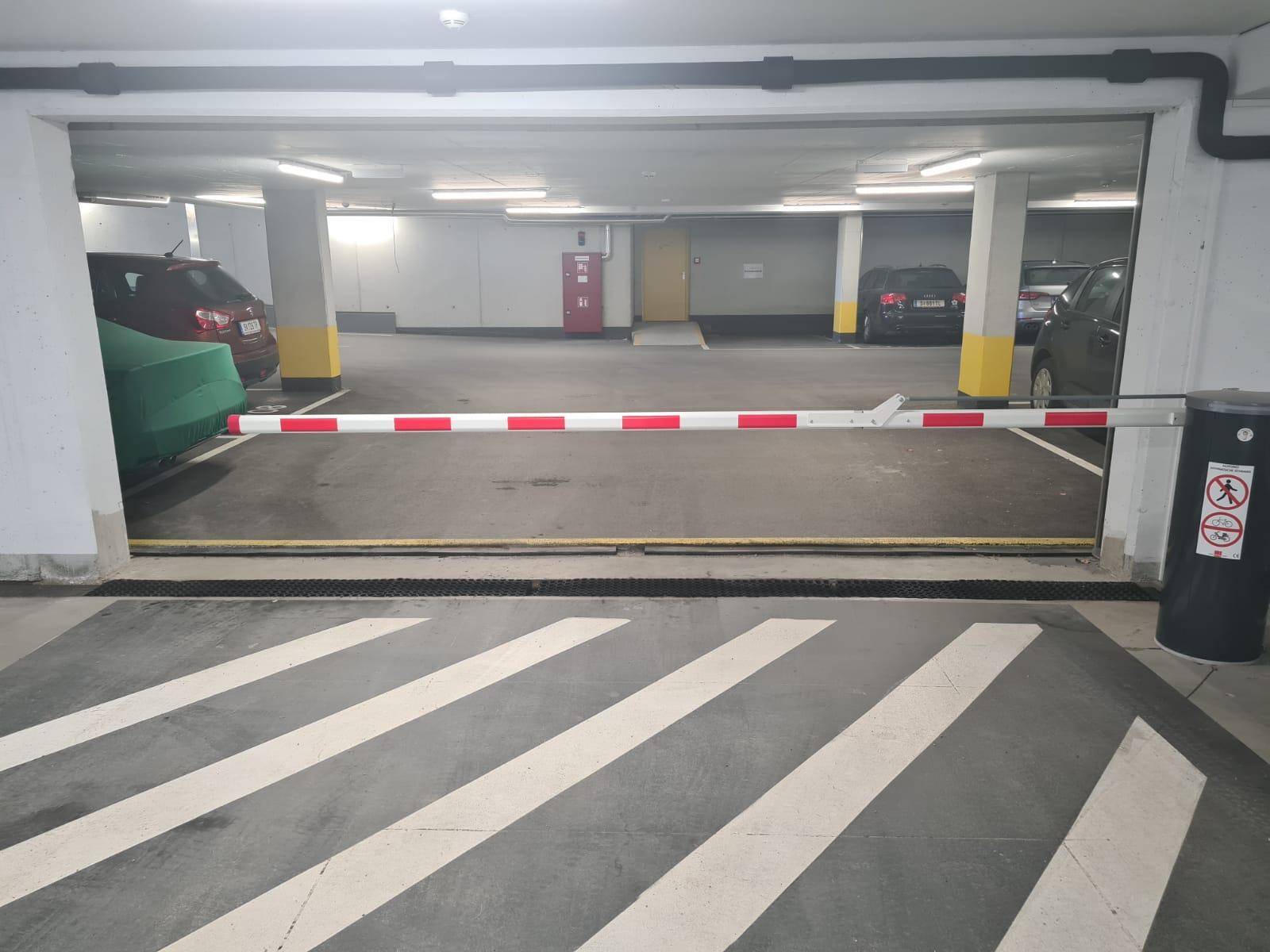 Innenansicht der Tiefgarage mit einer Zufahrtsschranke und markierten Parkflächen.