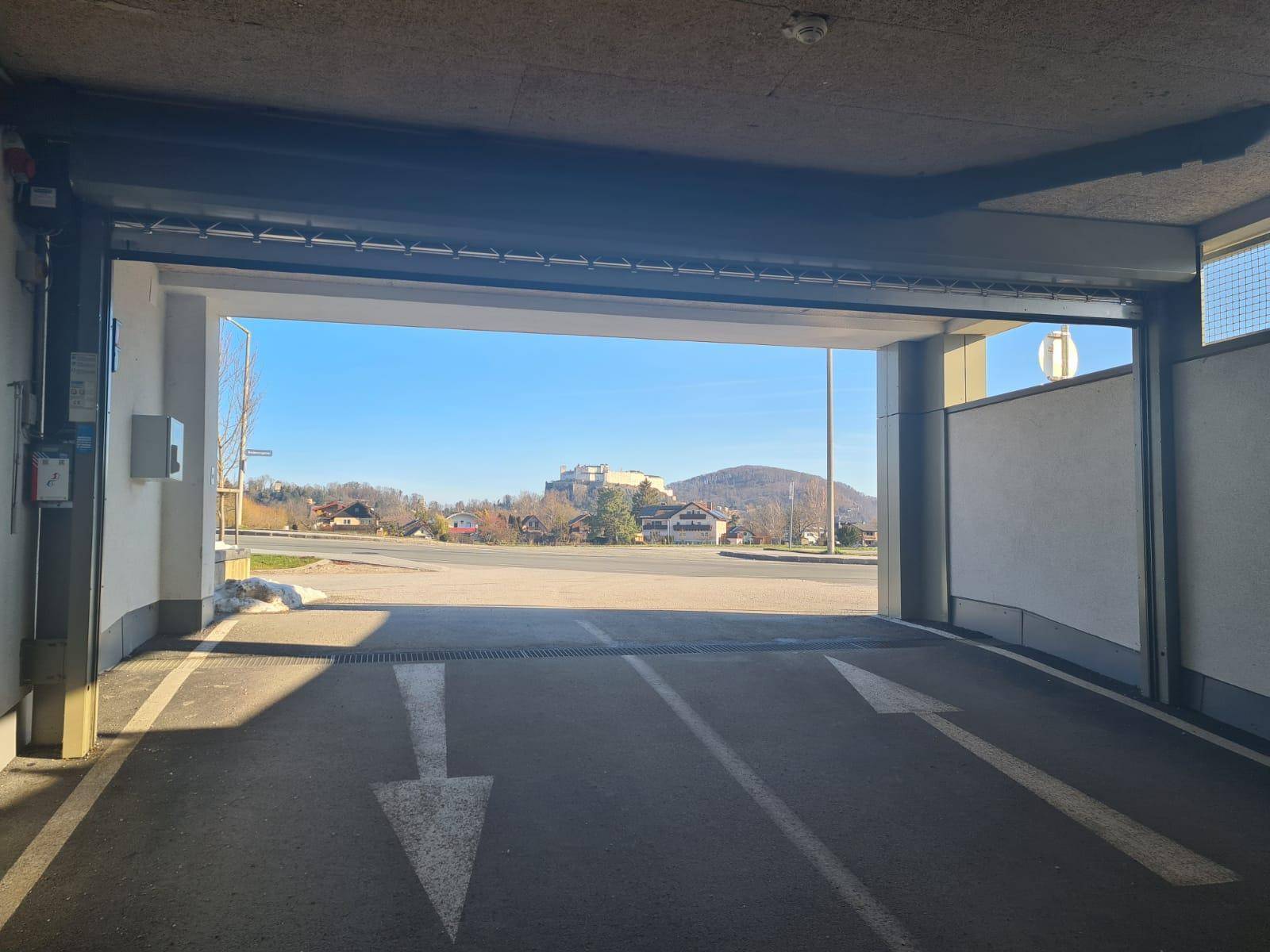 Ausfahrt der Tiefgarage mit Blick auf die umliegende Landschaft und eine historische Festung auf einem Hügel.