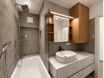 Modernes Badezimmer mit Badewanne, integrierter Dusche und stilvollem Waschtisch mit Spiegel.