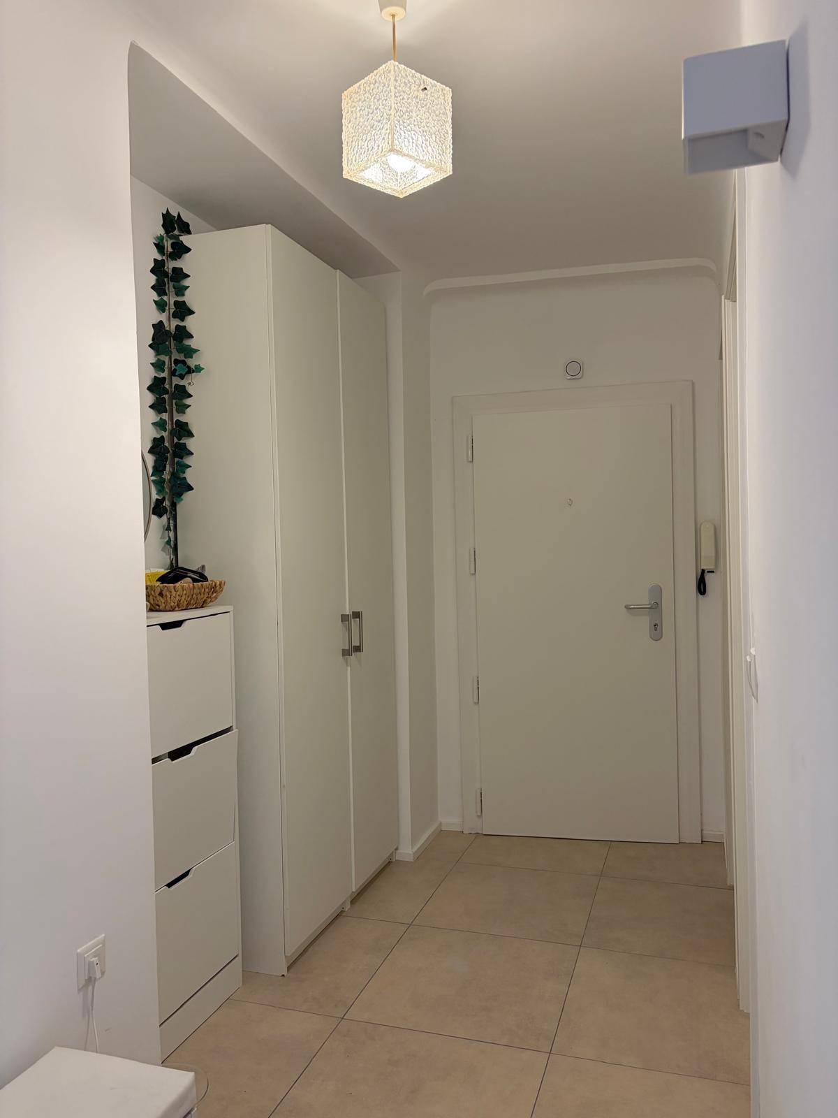 Heller Eingangsbereich mit Fliesenboden, praktischen Schränken und Zugang zur Wohnung.