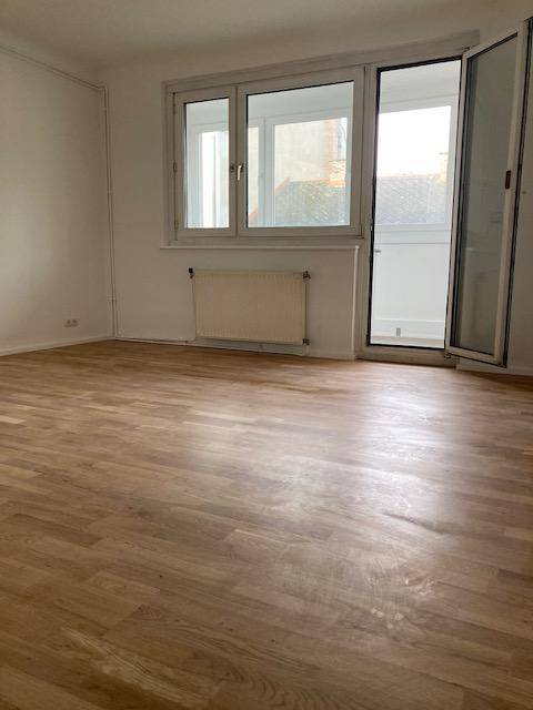 Heller Raum mit Parkettboden und direktem Zugang zu einem Balkon oder einer Loggia.