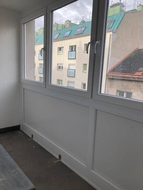 Verglaste Loggia mit Fenstern, die einen Blick auf die umliegenden Gebäude bieten.