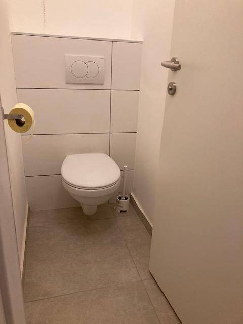 Kleines Gäste-WC mit wandhängender Toilette und modernen Fliesen an Wänden und Boden.