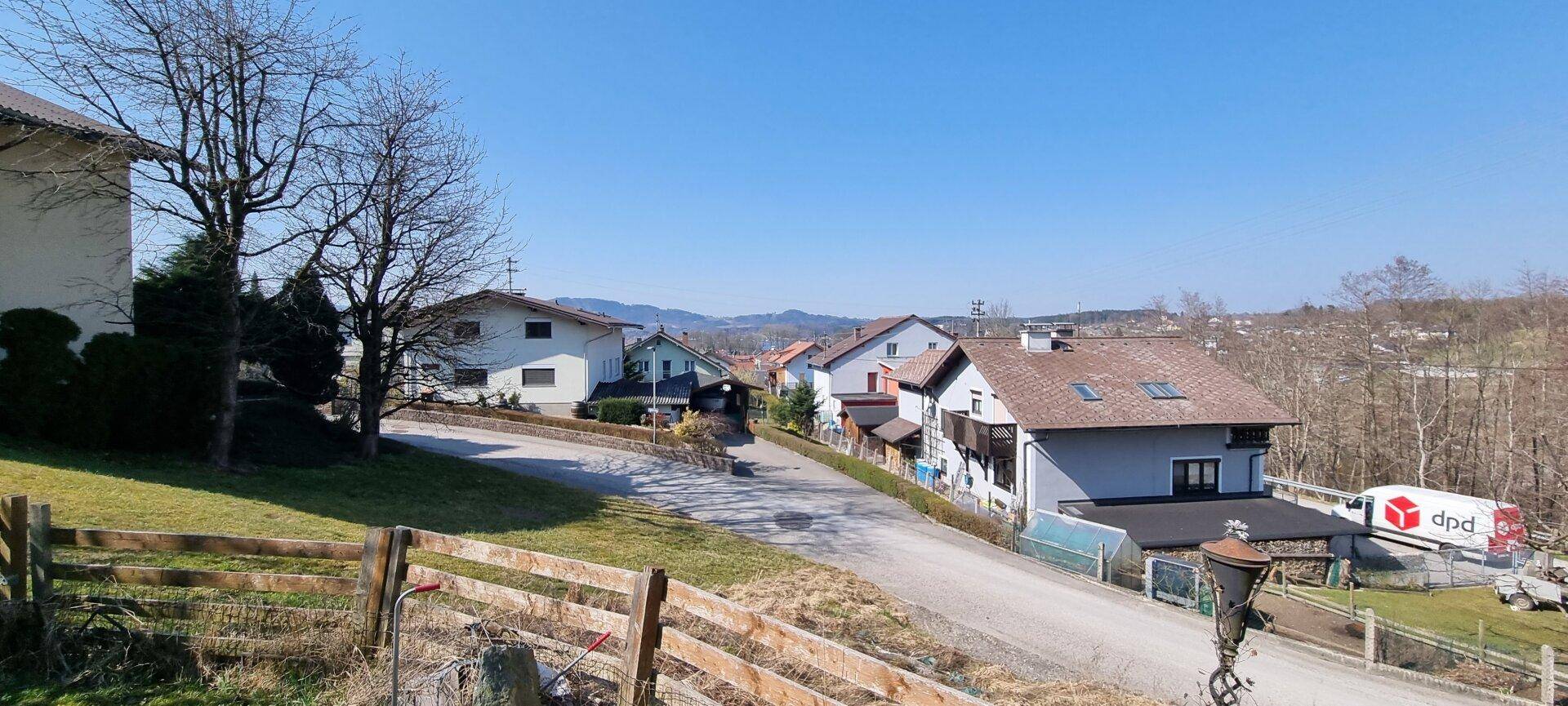 Panoramablick auf eine ruhige Wohngegend mit Einfamilienhäusern und bewaldeten Hängen.