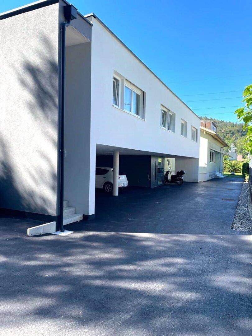 Moderne Gebäudefassade mit Carport und Parkmöglichkeiten im Freien.