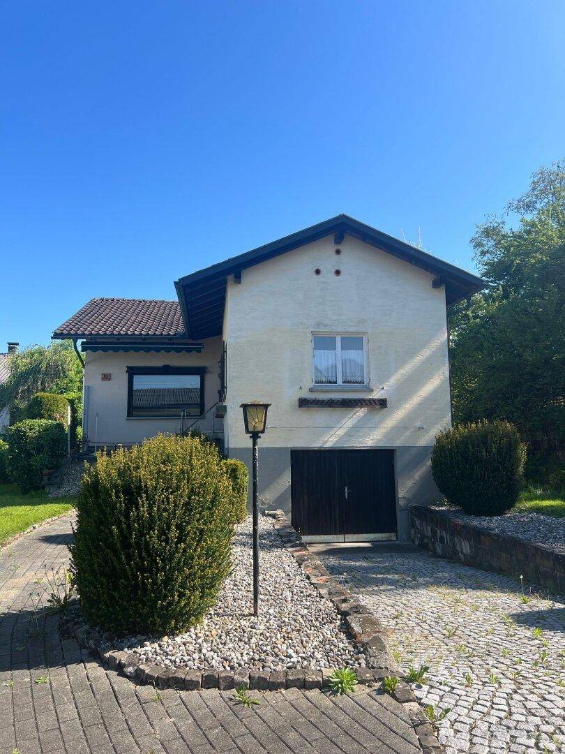 Vorderansicht des Einfamilienhauses mit Garage, gepflasterter Auffahrt und Laterne im Vorgarten.