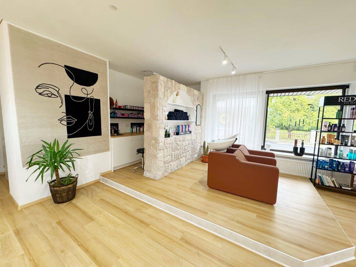 Erhöhter Bereich im Friseursalon mit Haarwaschbecken, Steinwand und moderner Wanddekoration.