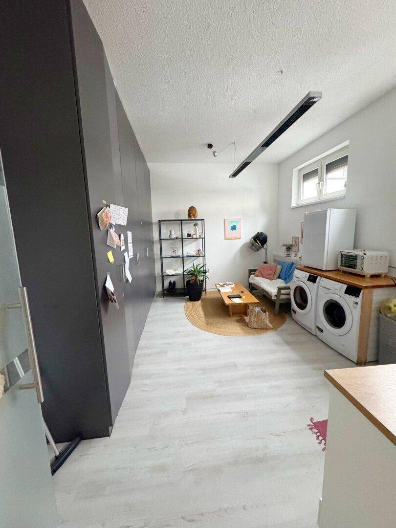 Funktionaler Raum mit Waschmaschine, Trockner, Kühlschrank und dunklen Einbauschränken.