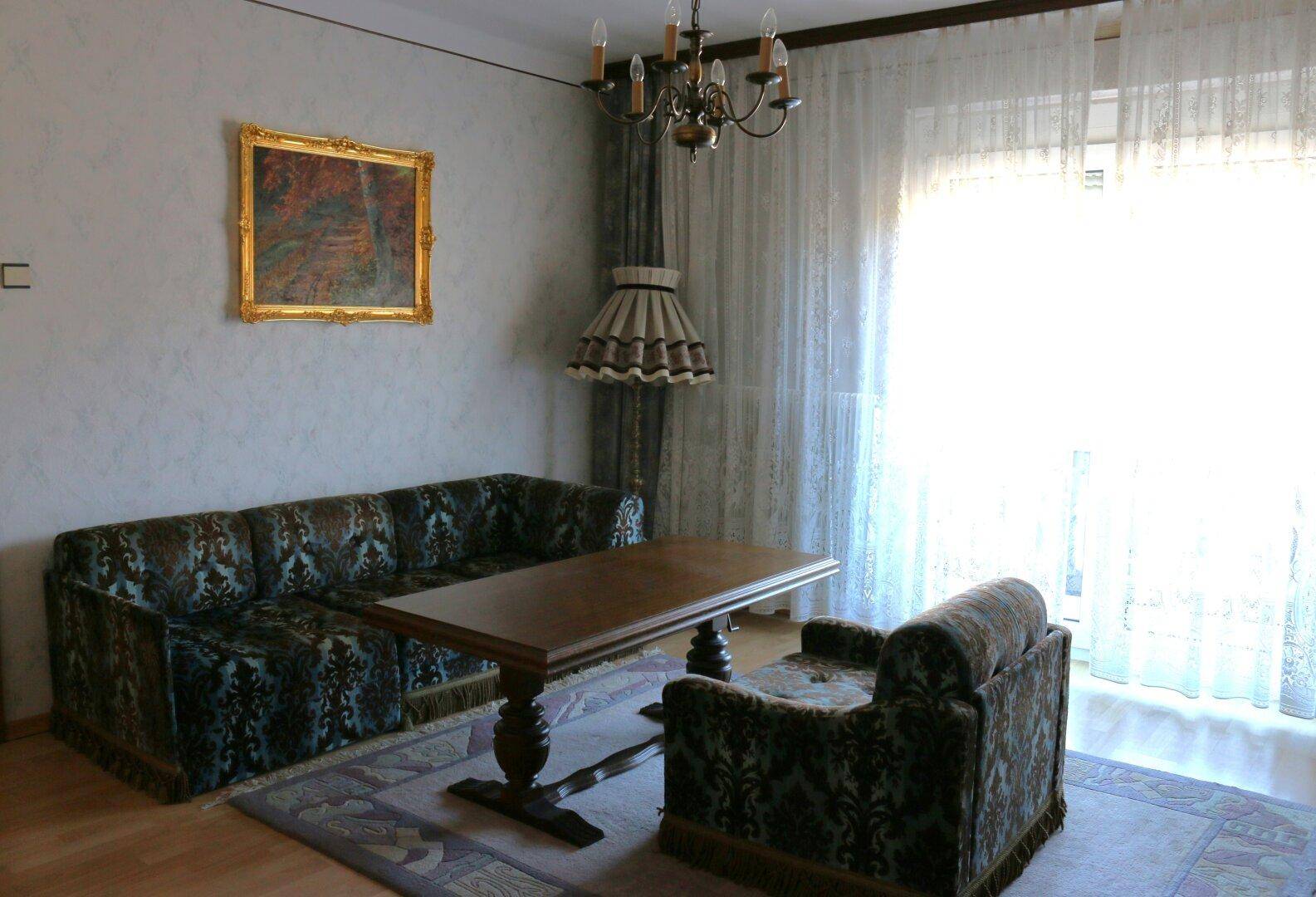 Wohnzimmer mit traditionellem Sofa, Couchtisch und großem Fenster.