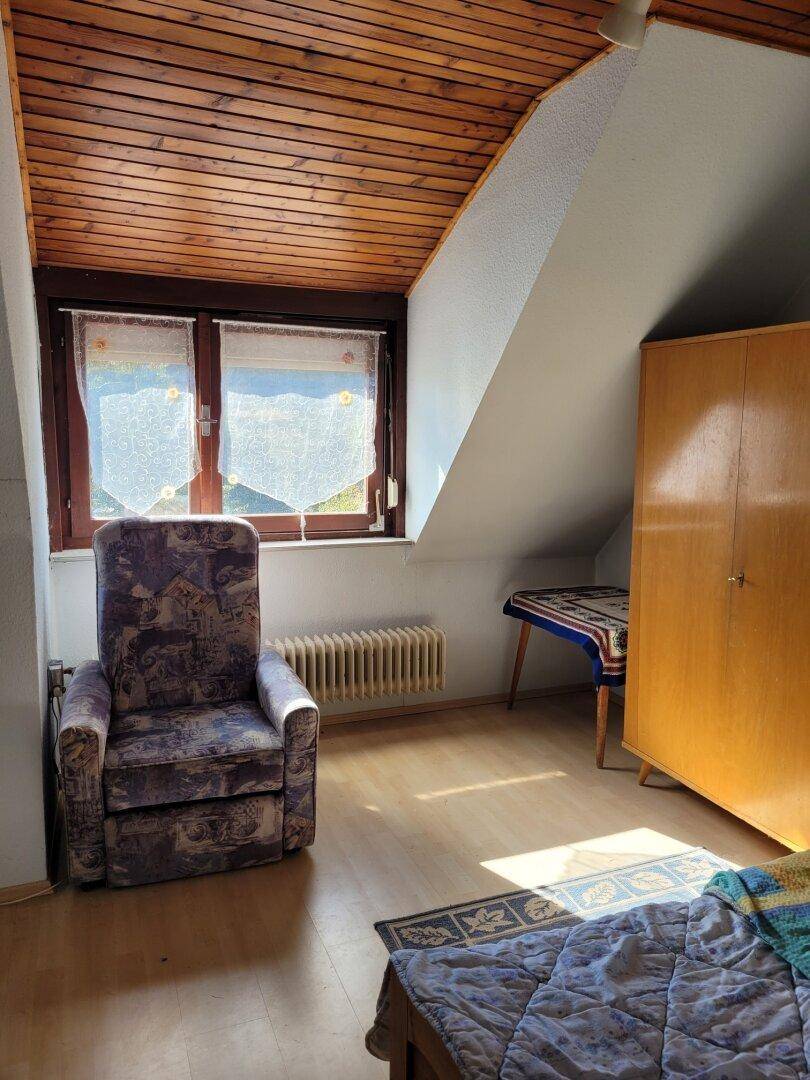 Helles Schlafzimmer im Dachgeschoss mit Holzdecke, Dachschräge und Fenster.