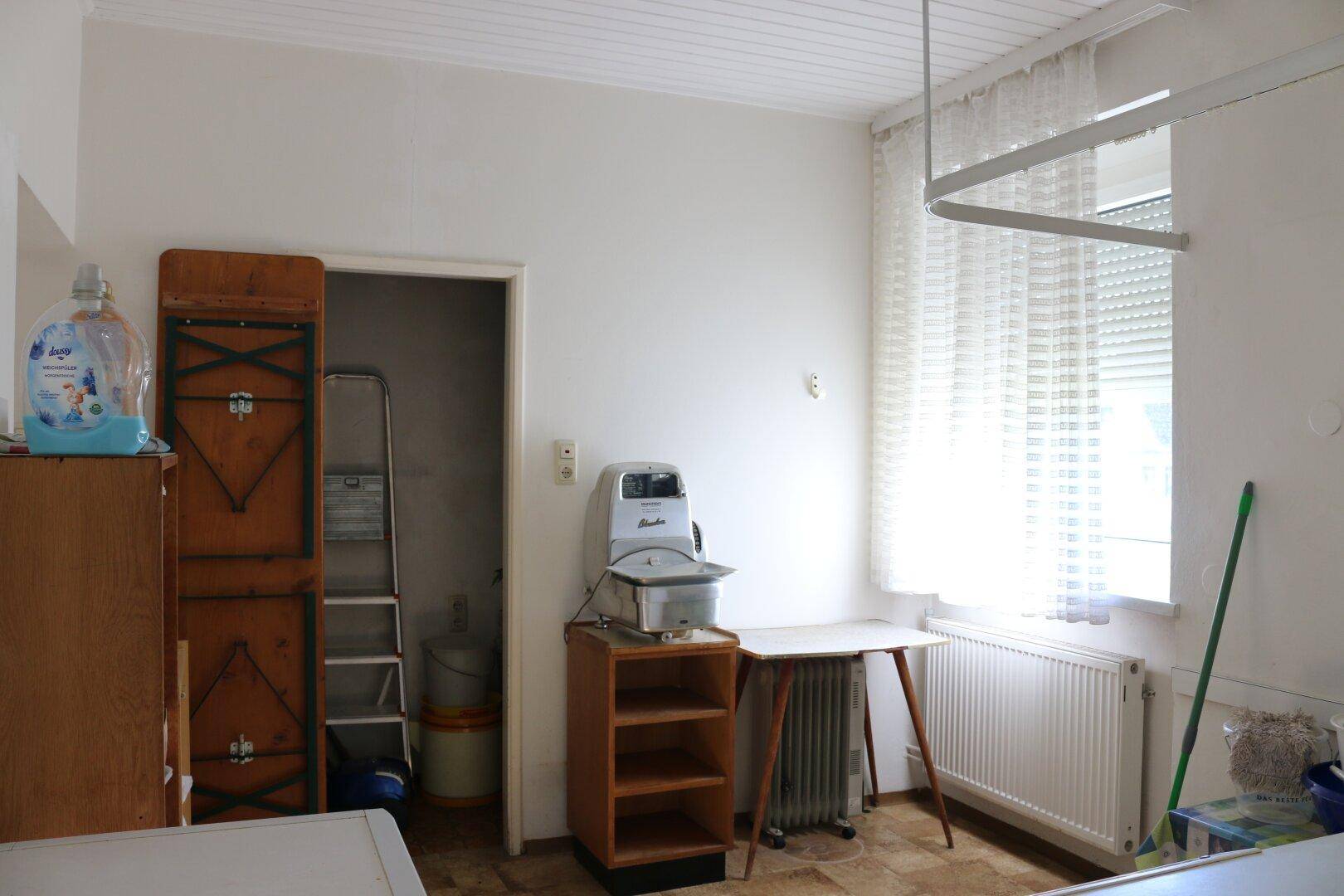 Heller Hauswirtschaftsraum mit Fenster, Heizkörper und praktischen Ablagemöglichkeiten.