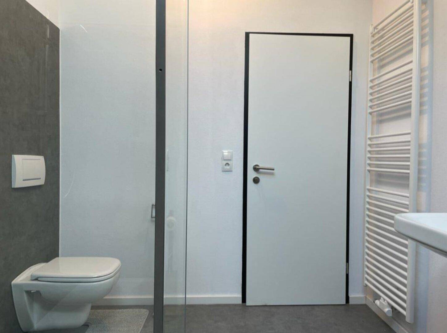Modernes Badezimmer mit begehbarer Dusche, Wand-WC und Handtuchheizkörper.
