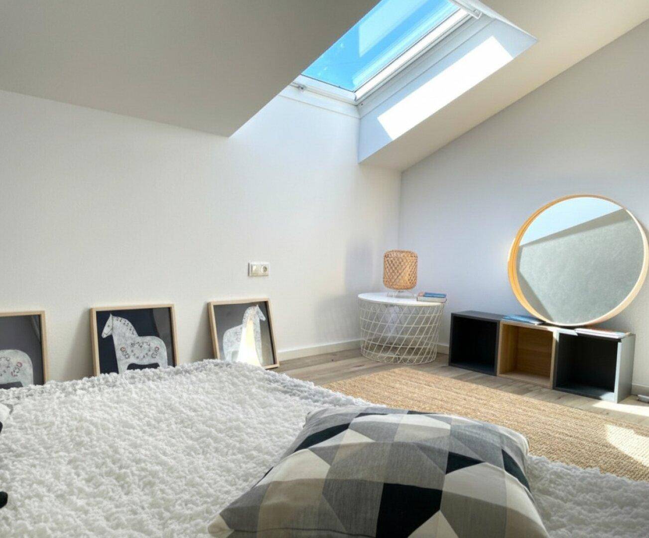 Helles Schlafzimmer mit Dachfenster, Teppich und moderner Dekoration.