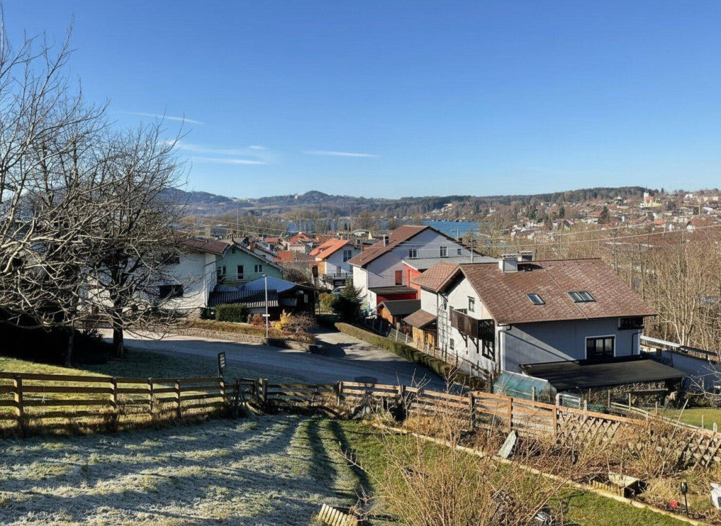 Weitläufiger Blick über eine Wohnsiedlung mit Häusern und Hügeln unter blauem Himmel.